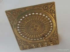 A Nap szimbólumával díszített réz asztali örök naptár