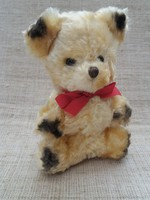 Old wool small teddy bear with glass eyes with a red ribbon around its neck