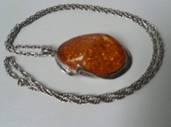 Large silver-plated pendant with an amber-colored stone on a long twisted chain