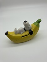 Snoopy money box resting on banana