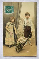 Antik grafikus romantikus képeslap kisleány és kisfiú talicska virággal