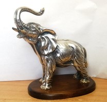 Silver-plated tin elephant statue with a raised arm on a wooden pedestal.