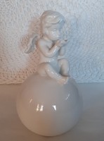 White porcelain angel sitting on a sphere, decoration