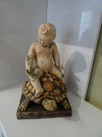 Antique marked ceramic turtle with putto traveling on its back.
