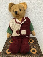 Antique straw teddy bear humming in knitted clothes