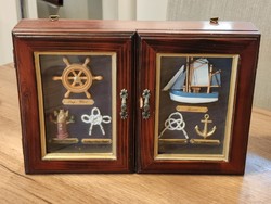Wall-mounted key cabinet with window decorated with a sailing ship and nautical paraphernalia