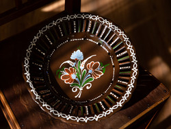 A large brown wall plate with an openwork edge with a flower pattern