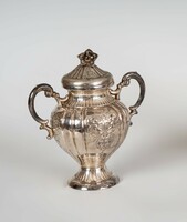 Sugar bowl with silver handles and a plastic flower on top