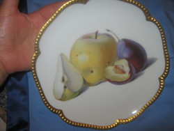 A plate with a gilded border with a fruit pattern