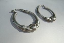 Hand holding a heart, silver hoop earrings (claddagh)