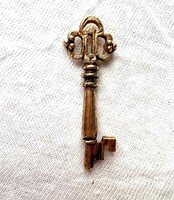 A miniature replica of a gold-colored bizsu church door key, a legacy of Inke László