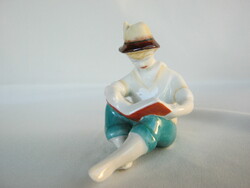 A boy reading a book from Hollóháza porcelain