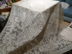 Pale cream-colored large lace tablecloth, bedspread, curtain.