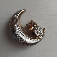 An owl perched on the moon, studded with many small sparkling stones, brooch pin