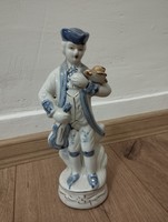 Porcelán barokk ruhás zenész madárral.