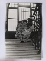 Régi fotó újságot olvasó férfi pizsamában egy bérház lépcsőjén ülve 1960-as évek