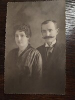 Keményített gallért és csokornyakkendőt visel, markáns bajusszal