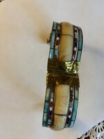 Nagyon szép bizsu karperec. Színes kagylóhéj berakással,réz csattal. A stiftet felhúzva nyitható.