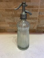 Ez egy antik szódásüveg vagy szifon, jellegzetes ónfejjel és bordázott üvegtesttel.