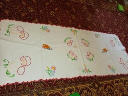 Régi hímzett asztalterítő, amely gomba- és virágmintával, valamint piros szegéllyel rendelkezik.