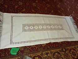 Egy fehér hímzett, azsúros terítő rojtos végekkel.