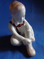 Aquincum porcelán figura, amely egy cipőt fűző kisfiút ábrázol.