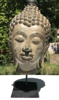 Bronz Buddha fej fa posztamensen.