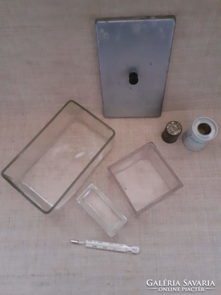 Old medical glass containers inside a thermometer with a metal case and a metal jar of wound adhesive