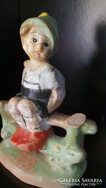 Antik, kerítésen ülő, kerámia kisfiú figura.