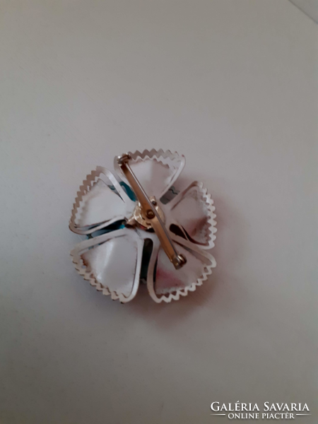 An old handmade enameled metal flower adorned with polished white stone in the middle