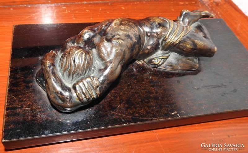 Lying suffering Jesus Christ - bronze statue on a wooden foundation