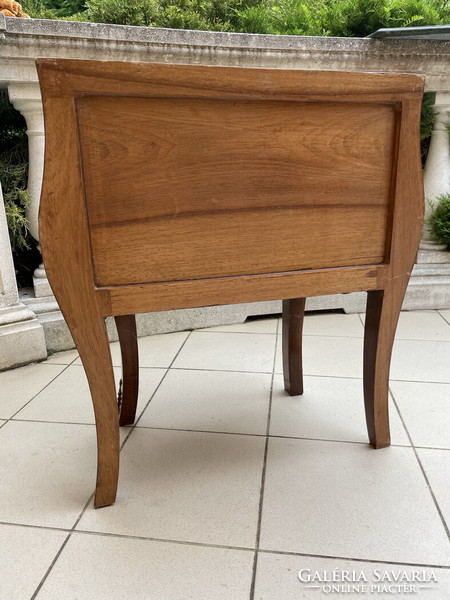 A small chest of drawers with a beautiful bent shape