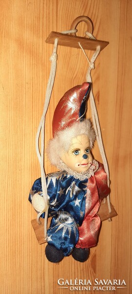 A clown with an old porcelain head sitting on a swing
