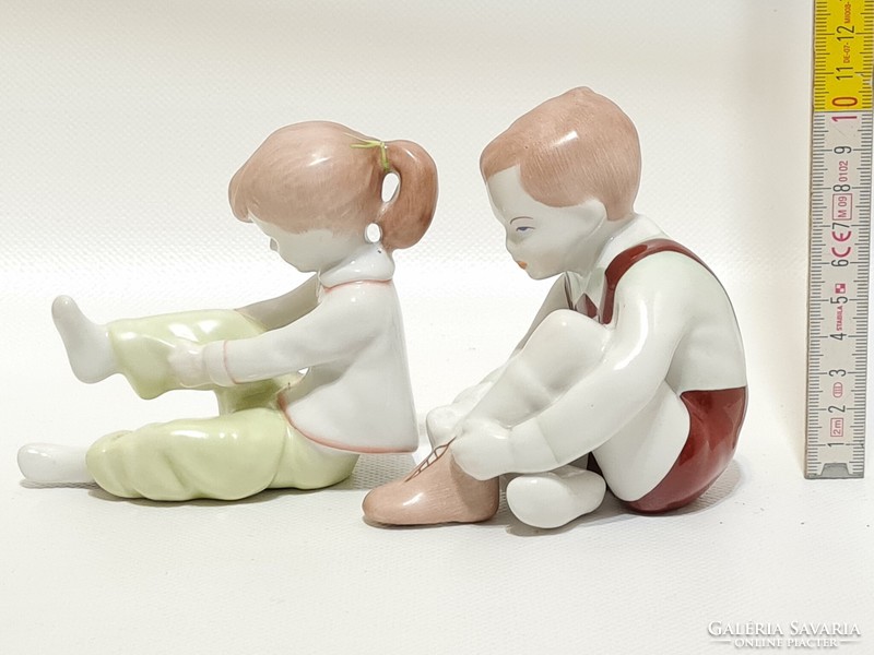 Aquincumi cipőt kötő kisfiú és öltözködő kislány porcelán figura 2 db (2285)