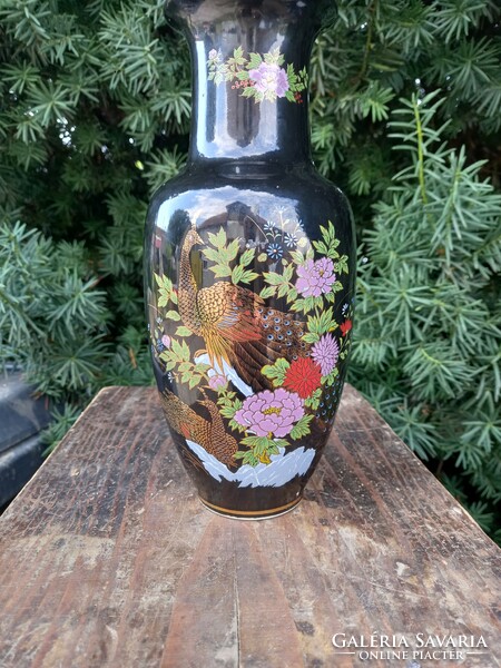 Beautiful Japanese porcelain vase with gold peacocks and flowers on a black background.