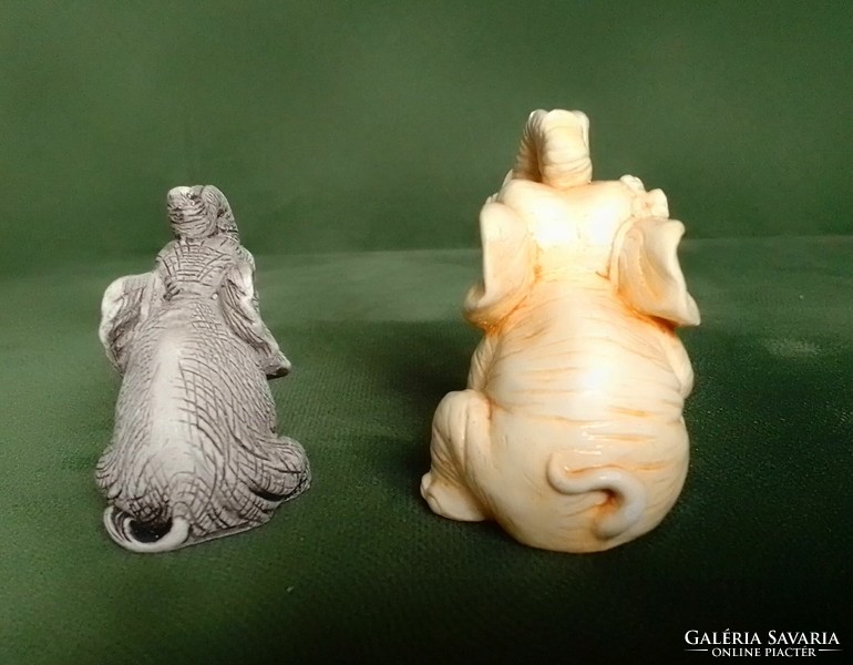 Two lucky sitting polyresin elephant figurines with raised trunks are hand painted