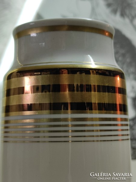 A cylindrical German porcelain vase with gold and black stripes on a white background