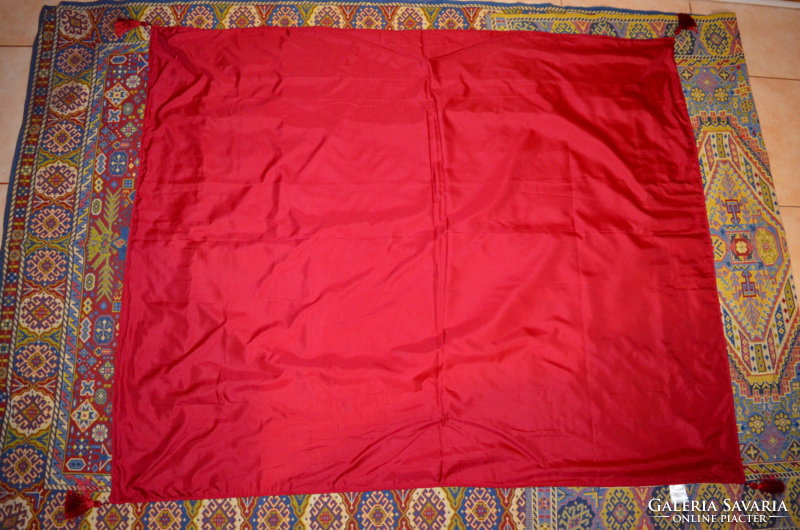 A tablecloth with a pattern woven in its material with a single tassel at the corners