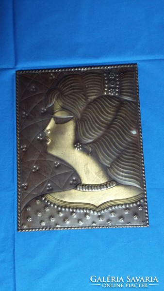 Copper mural depicting an old female head
