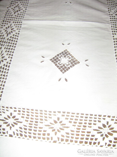A dreamy white needlework tablecloth with a sewn lace insert with a hand-crocheted edge