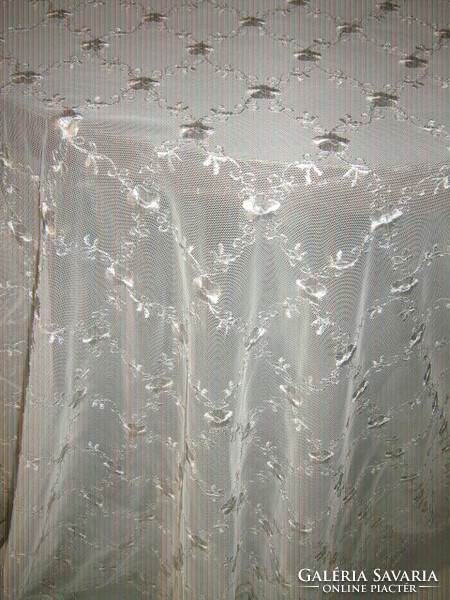A tulle curtain with a wavy, slinged bottom, embroidered with a bright flower in the special elegant fabric of Messezép