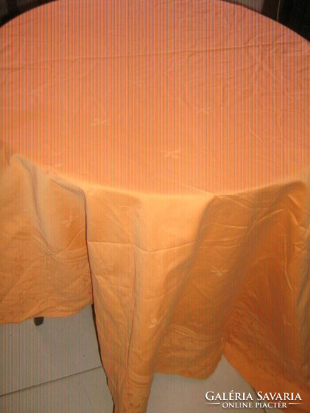 A beautiful oval damask tablecloth with a peach-yellow leaf pattern