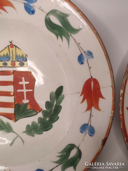 A pair of hard ceramic painted folk wall plates marked Hóllóháza with an old coat of arms