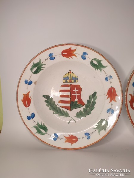 A pair of hard ceramic painted folk wall plates marked Hóllóháza with an old coat of arms