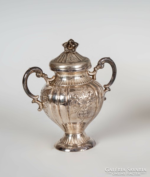 Sugar bowl with silver handles and a plastic flower on top