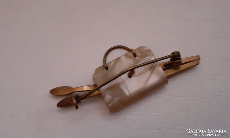 A small mother-of-pearl bag-shaped brooch holding a paint brush made with retro handwork
