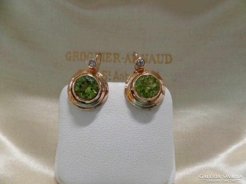 A pair of gold earrings with olivine and brils