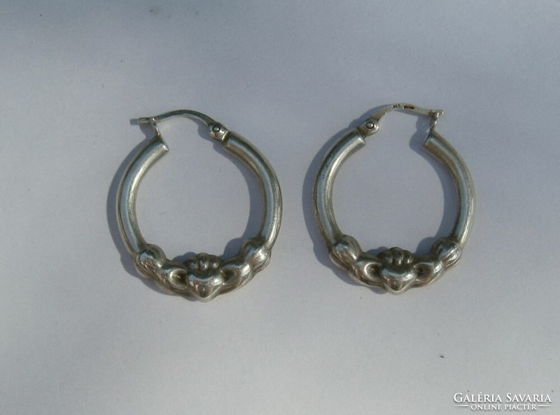 Hand holding a heart, silver hoop earrings (claddagh)