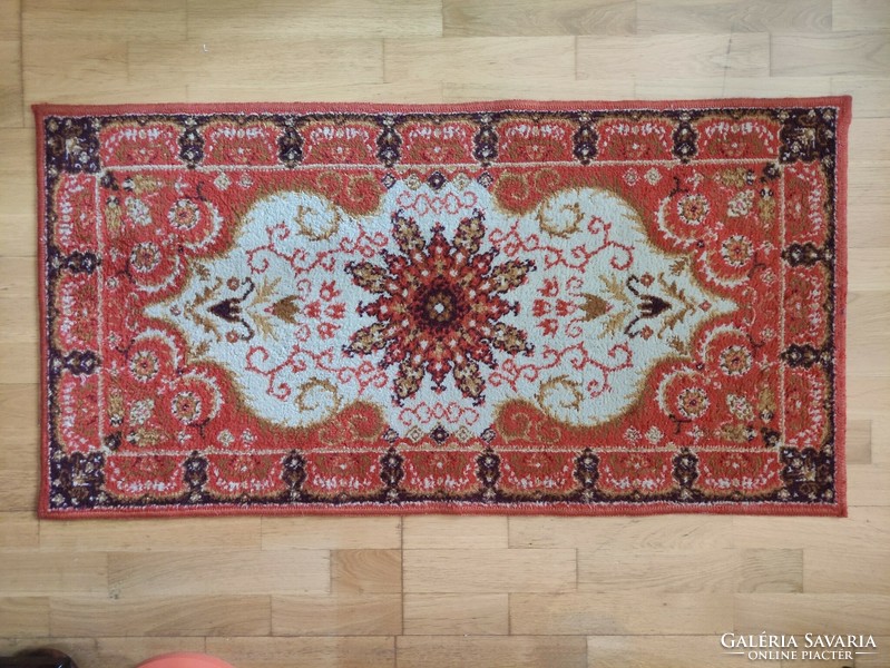 A small machine-made Persian carpet with a classic pattern in an orange tone