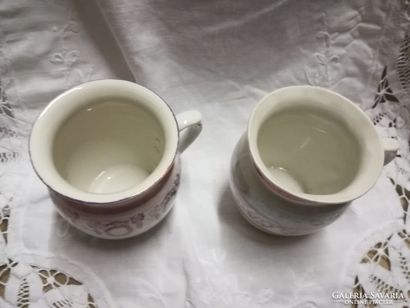 A pair of porcelain mugs with a similar pattern